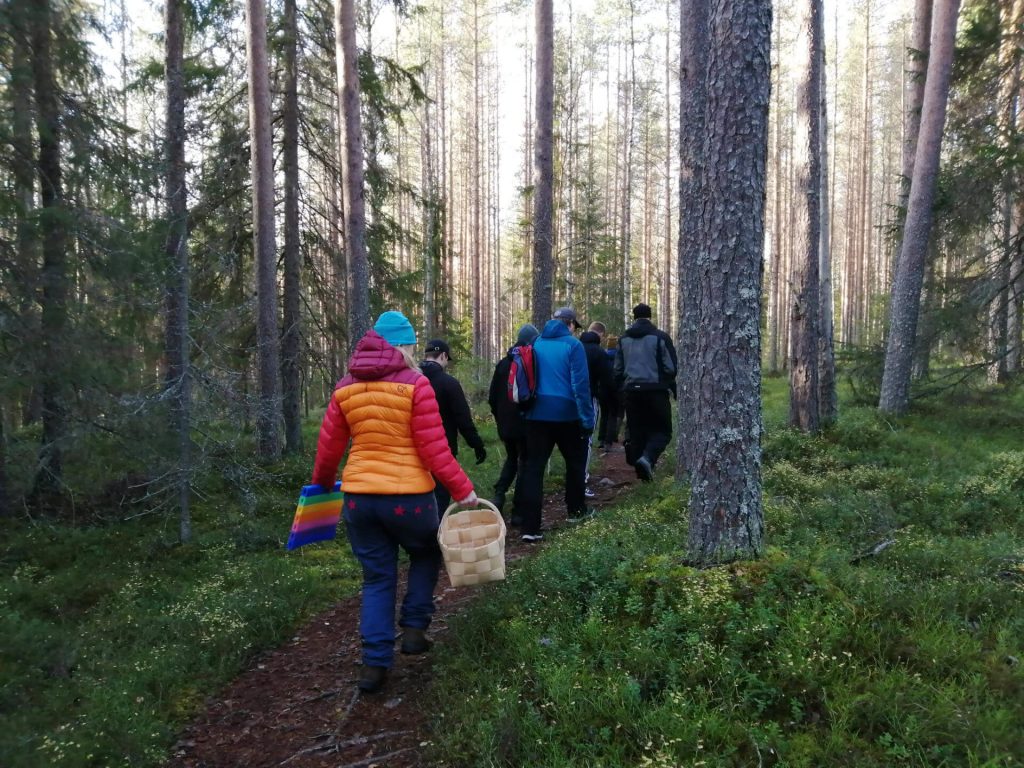 ryhmä ihmisiä kävelee metsässä